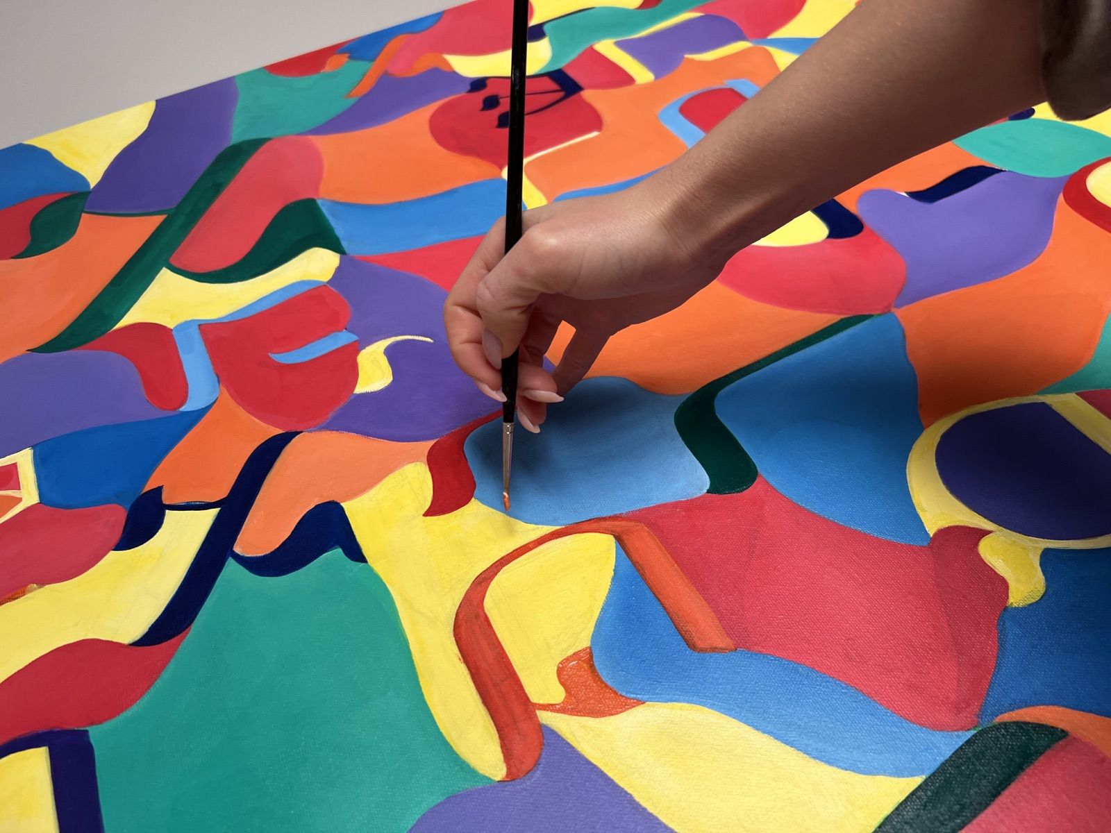 Im Atelier: Hand mit Pinsel an einer farbigen Komposition